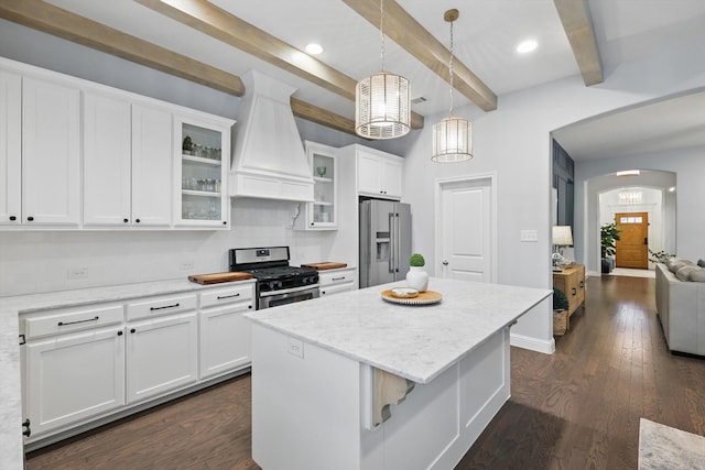 kitchen with beam ceiling, arched walkways, stainless steel appliances, custom exhaust hood, and white cabinetry