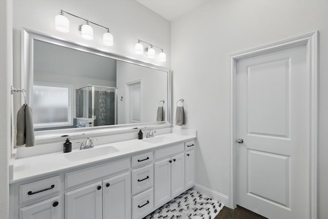 full bath with a sink, baseboards, double vanity, and a shower stall