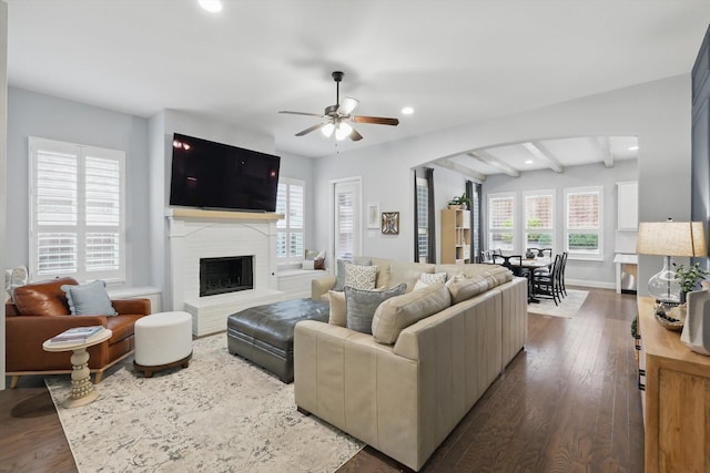 living room featuring a ceiling fan, wood finished floors, recessed lighting, arched walkways, and a brick fireplace