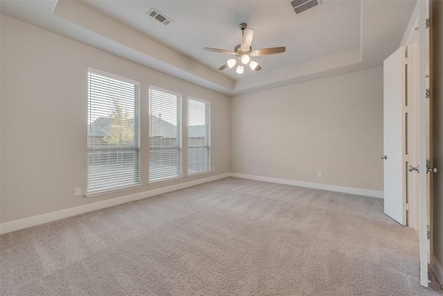 unfurnished room with a raised ceiling, light colored carpet, and visible vents