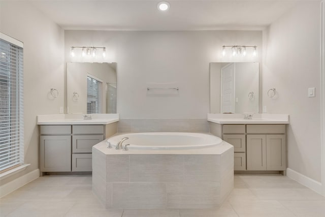 bathroom featuring two vanities, a bath, and a sink