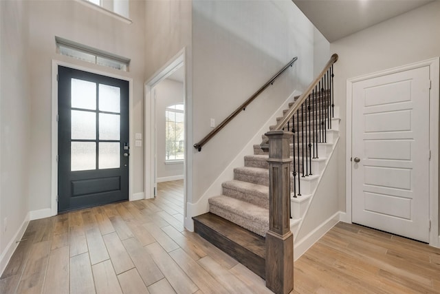 foyer entrance with light wood-style flooring, stairs, and baseboards