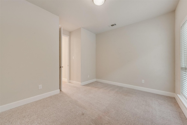 empty room featuring visible vents, light carpet, and baseboards