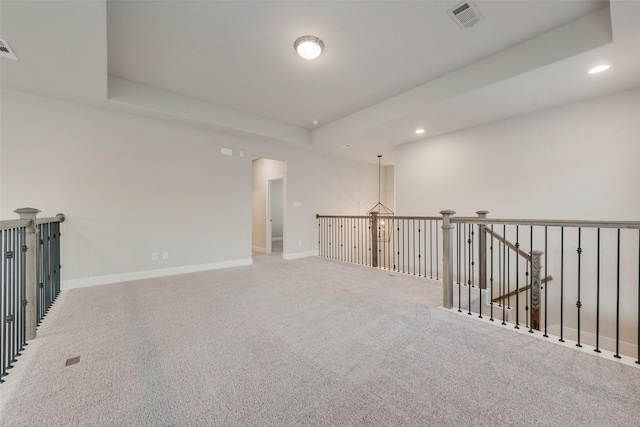 carpeted spare room featuring recessed lighting, a tray ceiling, baseboards, and visible vents