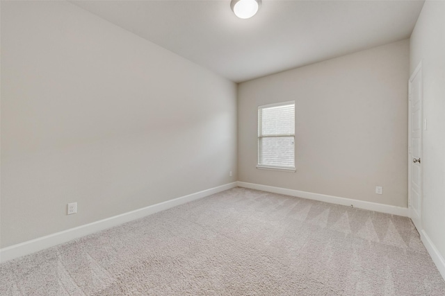 spare room with baseboards and light carpet