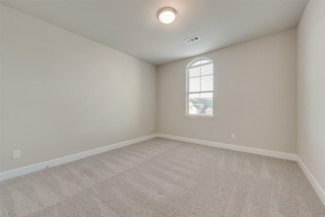 spare room featuring visible vents, light carpet, and baseboards