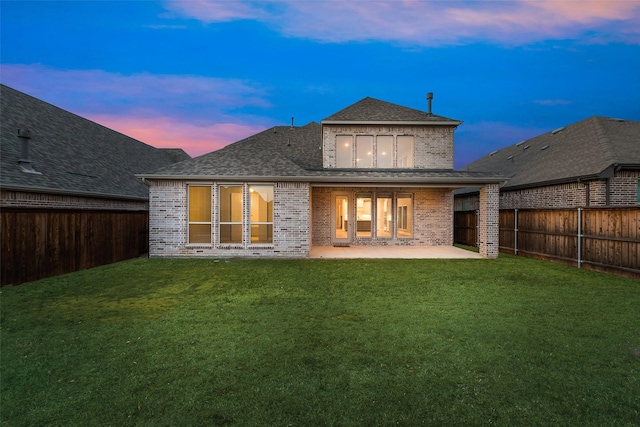 back of house featuring brick siding, a lawn, a patio, and a fenced backyard