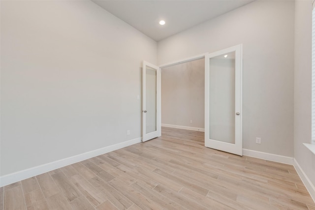 spare room featuring recessed lighting, french doors, light wood-type flooring, and baseboards