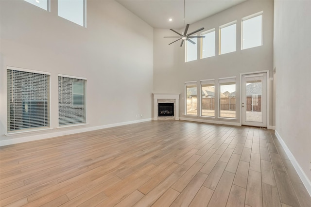 unfurnished living room featuring a ceiling fan, baseboards, light wood-style flooring, recessed lighting, and a glass covered fireplace