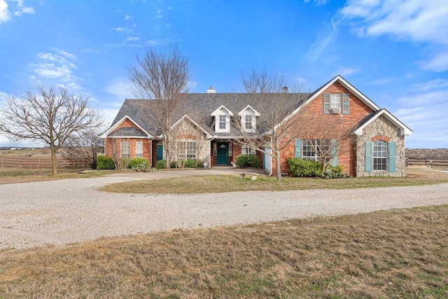 view of front facade with driveway, stone siding, brick siding, and a front lawn