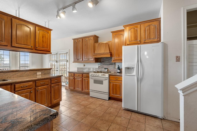 kitchen featuring premium range hood, white appliances, and brown cabinets