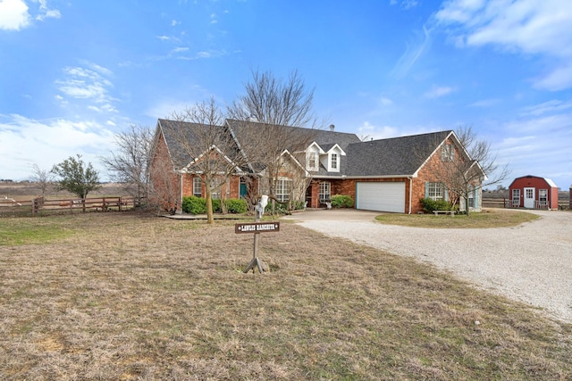 view of front of house with brick siding, gravel driveway, a front lawn, and fence