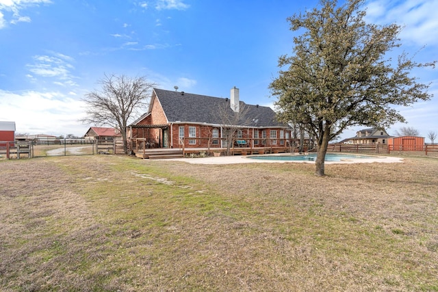 rear view of property with a gate, fence, a deck, a lawn, and brick siding