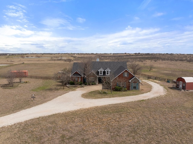 view of front of home featuring a rural view, curved driveway, and fence