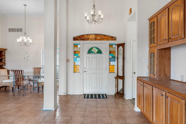 foyer entrance with visible vents, an inviting chandelier, light tile patterned flooring, baseboards, and a towering ceiling