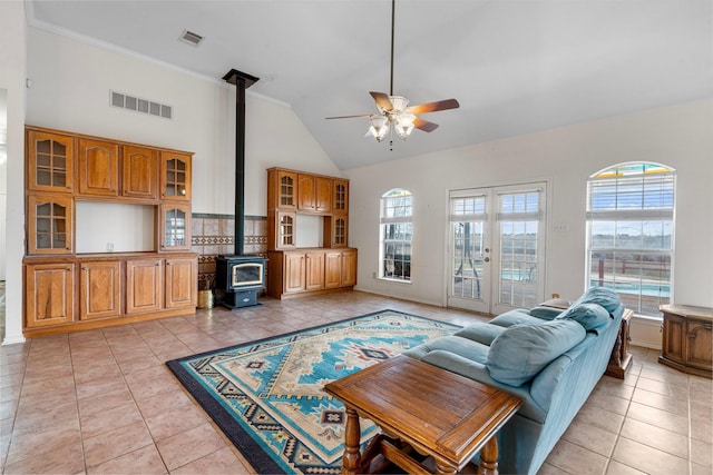 living area with light tile patterned flooring, visible vents, plenty of natural light, and a wood stove