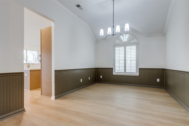 spare room featuring a wainscoted wall, light wood-style floors, and crown molding