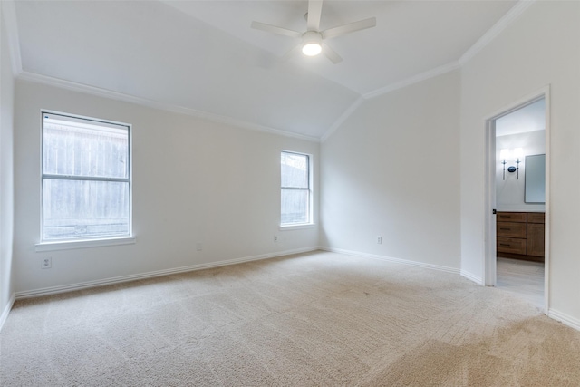 spare room with light carpet, ornamental molding, a ceiling fan, baseboards, and vaulted ceiling