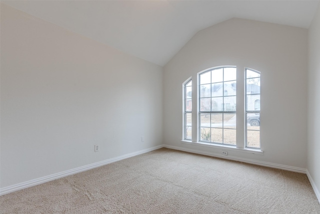 carpeted spare room with lofted ceiling and baseboards