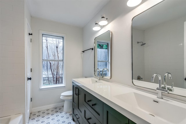 bathroom with toilet, double vanity, walk in shower, and a sink