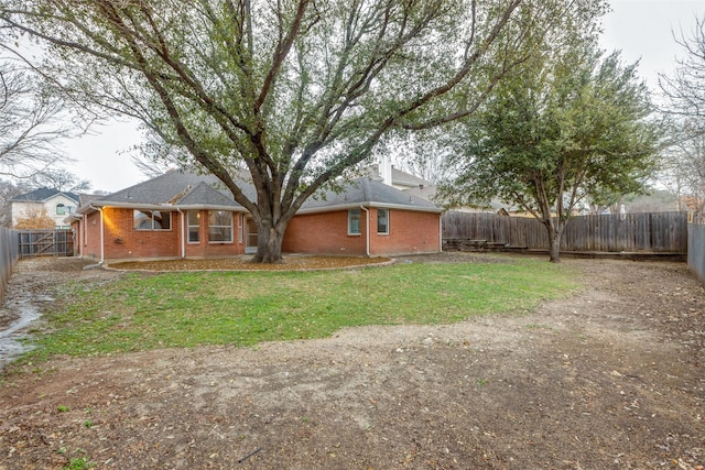 exterior space with a yard, a fenced backyard, and brick siding