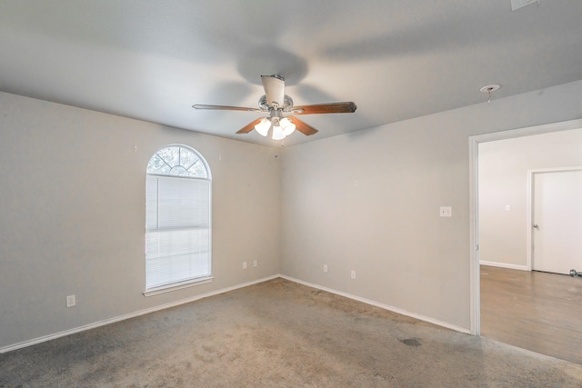 carpeted spare room featuring a ceiling fan and baseboards