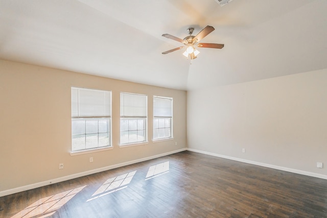 empty room with dark wood finished floors, ceiling fan, baseboards, and vaulted ceiling