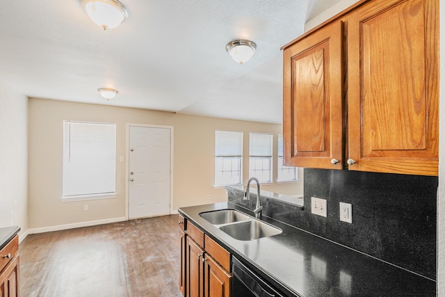 kitchen with dark countertops, brown cabinetry, light wood finished floors, and a sink