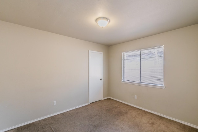 carpeted empty room featuring baseboards