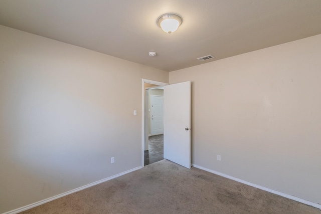 carpeted spare room with visible vents and baseboards