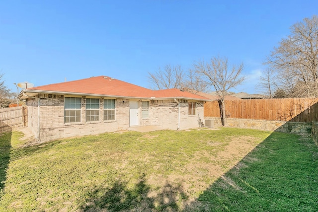 back of property with a yard, a fenced backyard, and brick siding