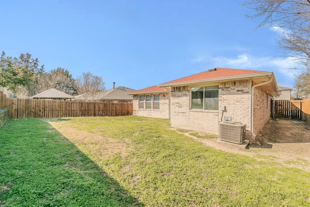 back of property featuring central air condition unit, a lawn, brick siding, and a fenced backyard