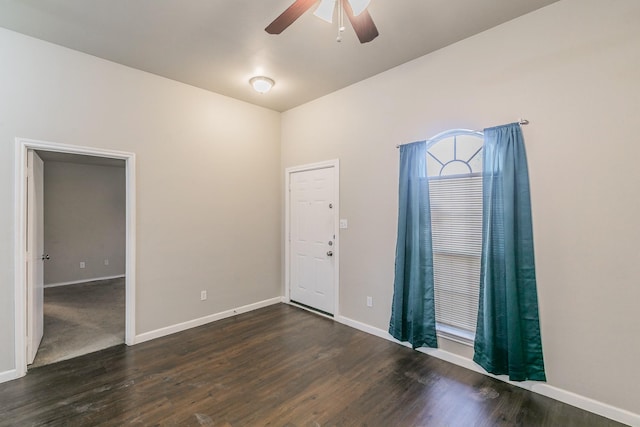 spare room featuring baseboards, dark wood-type flooring, and ceiling fan