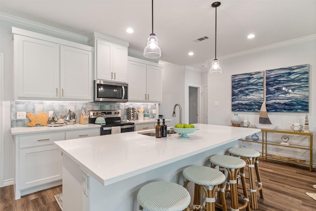 kitchen with decorative backsplash, white cabinetry, stainless steel appliances, and crown molding