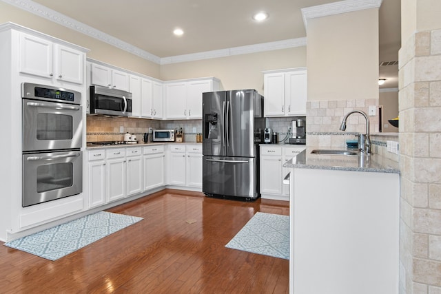 kitchen with a sink, tasteful backsplash, dark wood finished floors, stainless steel appliances, and crown molding