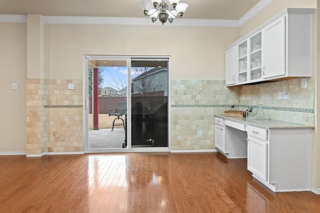 unfurnished dining area with ornamental molding, baseboards, an inviting chandelier, and wood finished floors