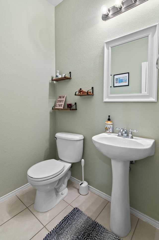 bathroom featuring tile patterned floors, toilet, baseboards, and a sink