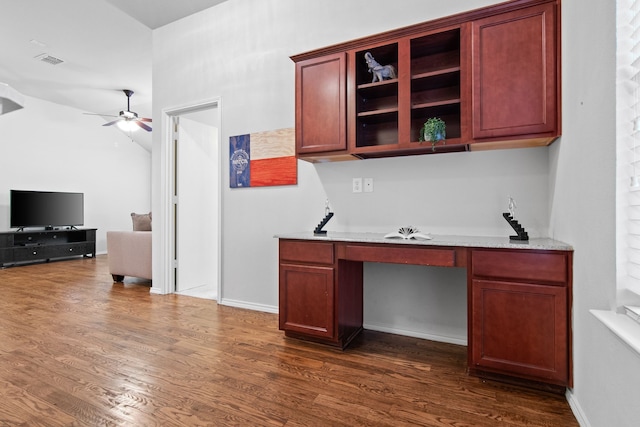 office featuring visible vents, a ceiling fan, baseboards, dark wood-style flooring, and built in study area