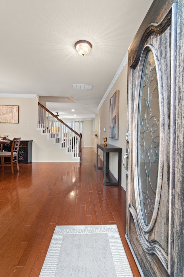 foyer with stairs, wood finished floors, visible vents, and ornamental molding