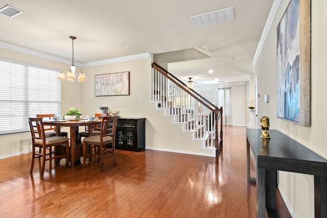 dining space featuring visible vents, wood finished floors, stairs, and ornamental molding