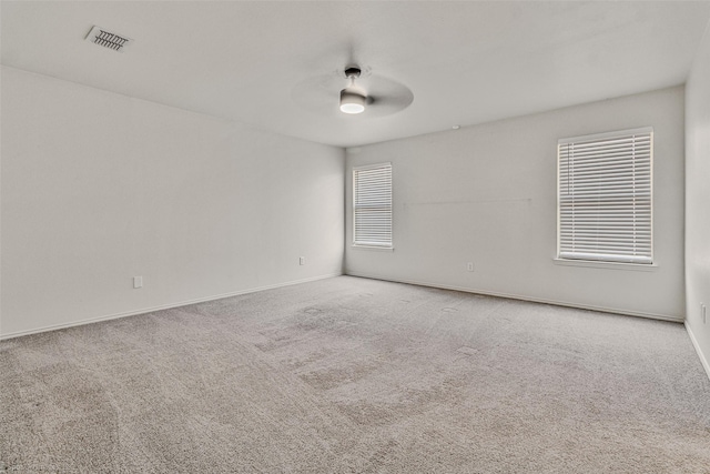 carpeted empty room with a ceiling fan, visible vents, and baseboards