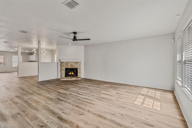 unfurnished living room featuring visible vents, plenty of natural light, and a fireplace