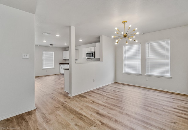 unfurnished living room featuring light wood-type flooring, visible vents, a notable chandelier, recessed lighting, and baseboards