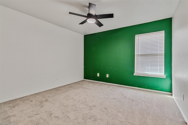 carpeted empty room featuring a ceiling fan and baseboards