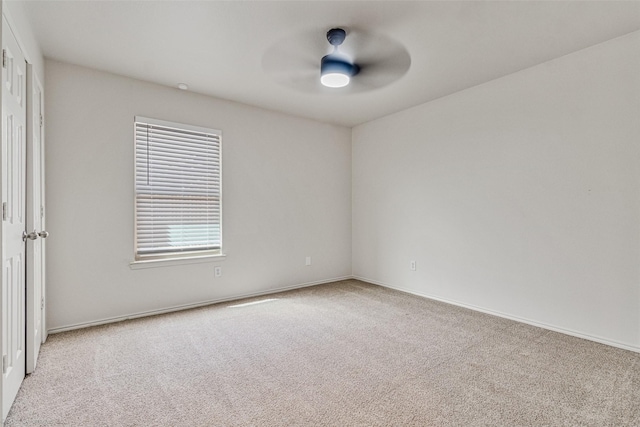 carpeted spare room featuring baseboards and ceiling fan