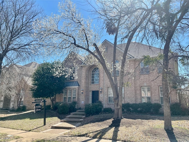 view of front facade with brick siding and a front lawn