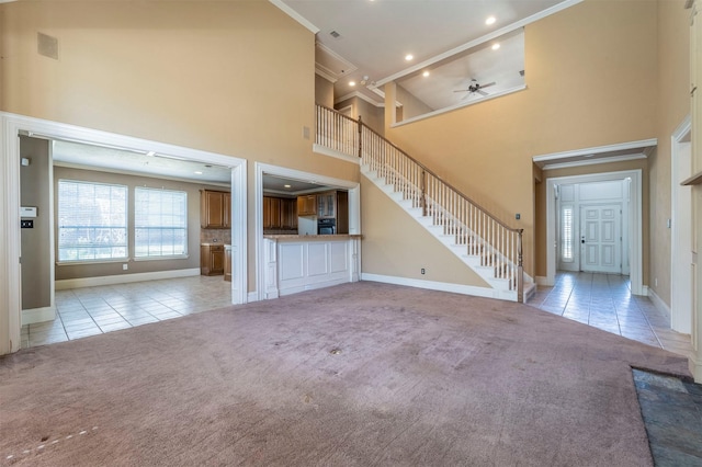 unfurnished living room with light tile patterned floors, light carpet, a high ceiling, and stairs