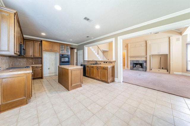 kitchen with visible vents, open floor plan, light countertops, black appliances, and a sink