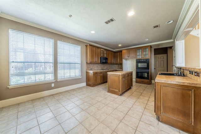 kitchen featuring a sink, visible vents, brown cabinets, and crown molding