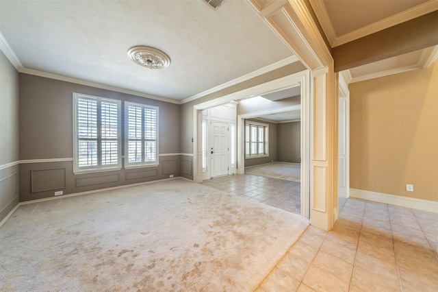 unfurnished room with a wainscoted wall, ornamental molding, tile patterned flooring, and a decorative wall